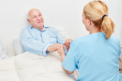 caregiver and senior holding hands while smiling