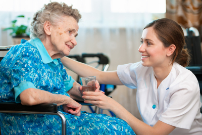 caregiver giving a glass of water to senior woman